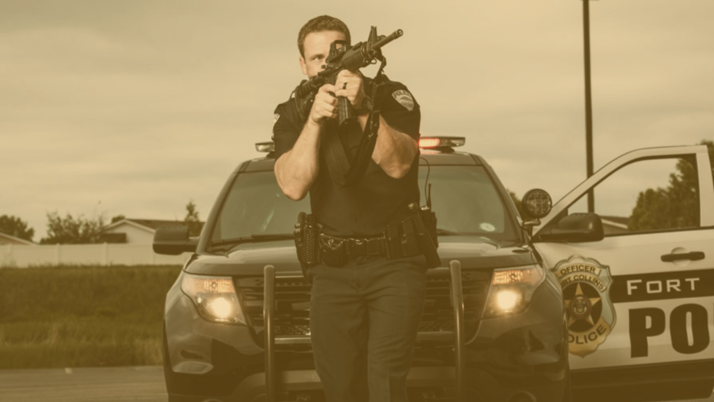 Police Officer walking with Rifle in front of police vehicle