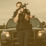 Police Officer walking with Rifle in front of police vehicle