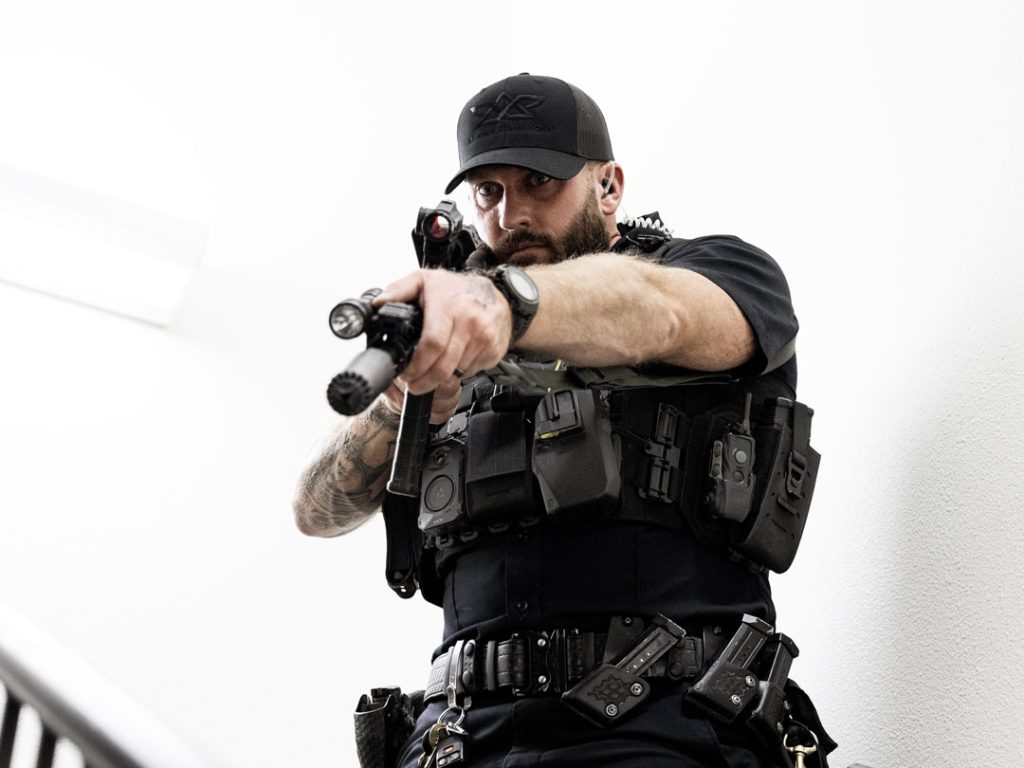 Officer advancing down a stairwell with rifle raised while wearing the Patrol Carrier 2.0, demonstrating stability, mobility, and secure equipment placement in tight environments.