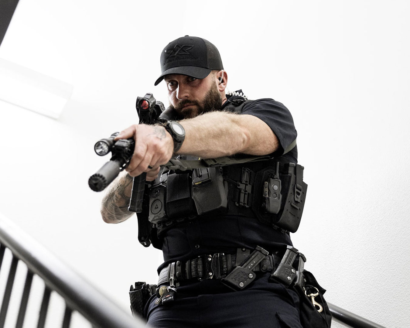 Officer advancing down a stairwell with rifle raised while wearing the Patrol Carrier 2.0, demonstrating stability, mobility, and secure equipment placement in tight environments.